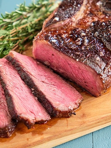 Sliced sous vide chuck steak on a wood carving board