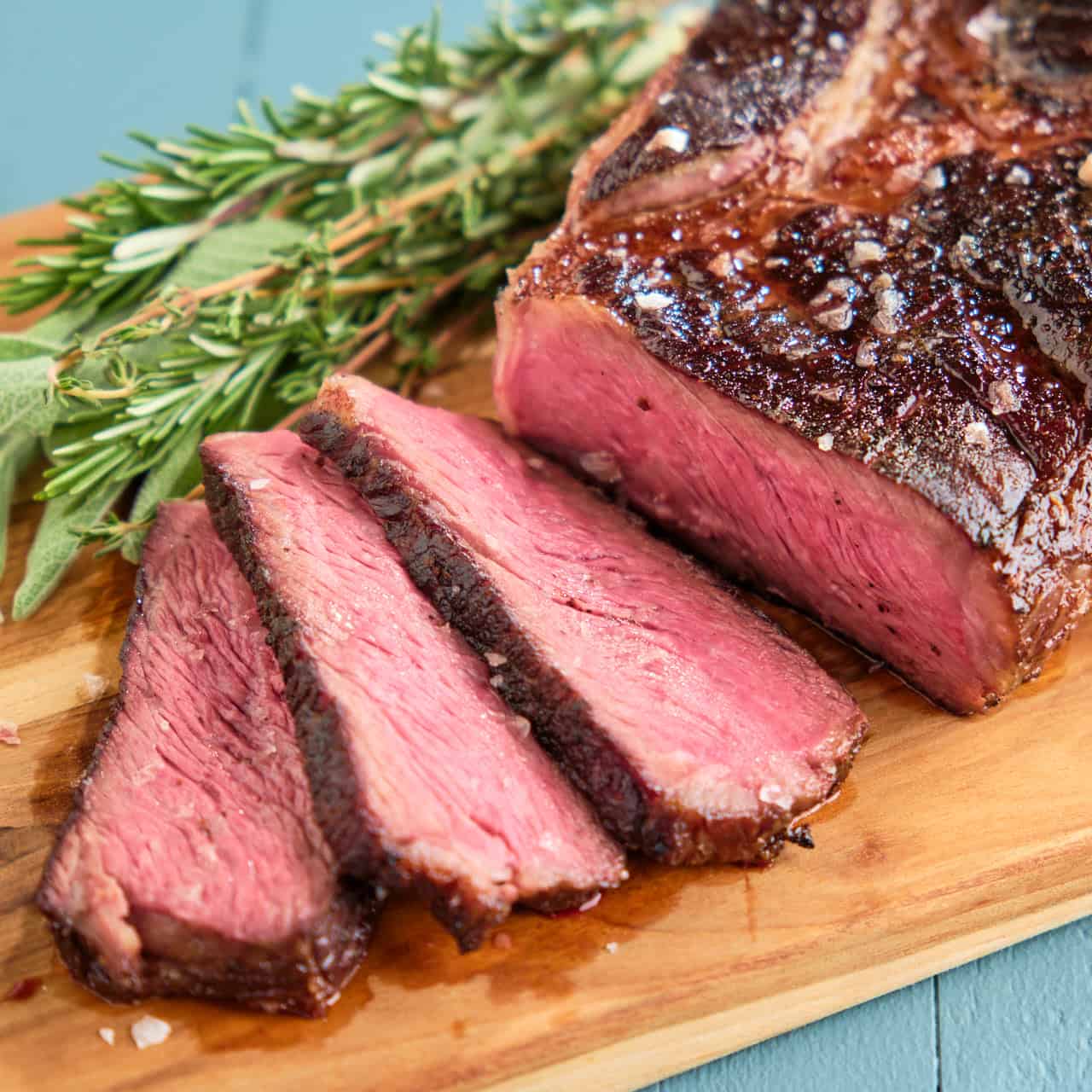 Sliced sous vide chuck steak on a wood carving board