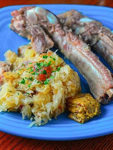 A plate of sauerkraut and pork ribs with mustard