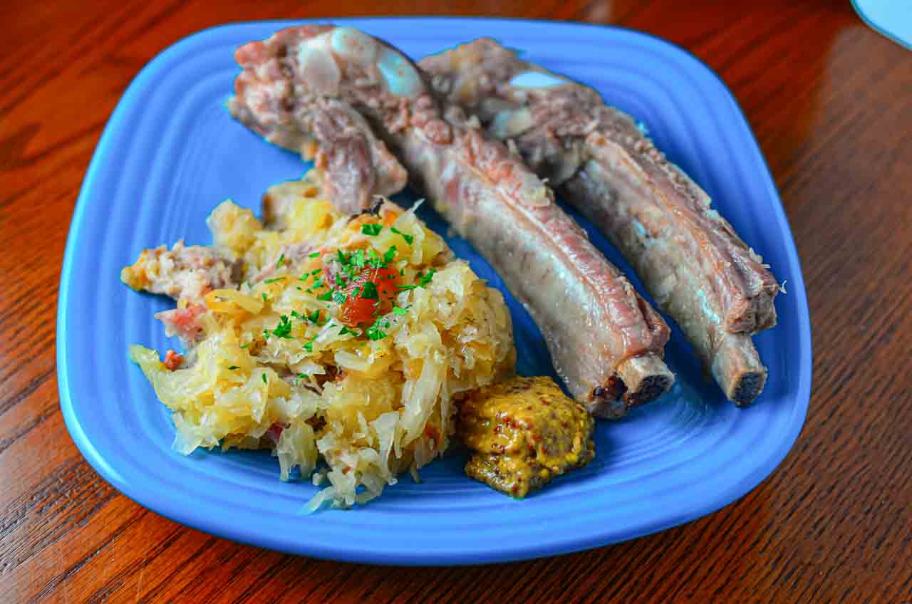 A plate of sauerkraut and pork ribs with mustard