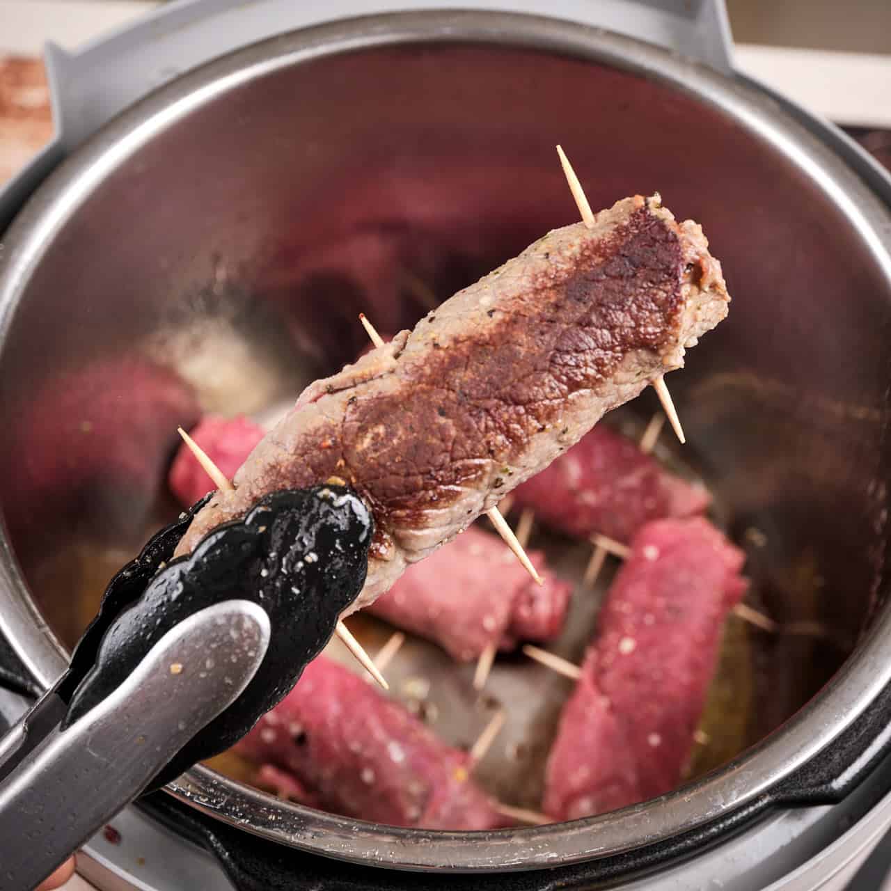 A browned roll of beef braciole with an Instant Pot in the background