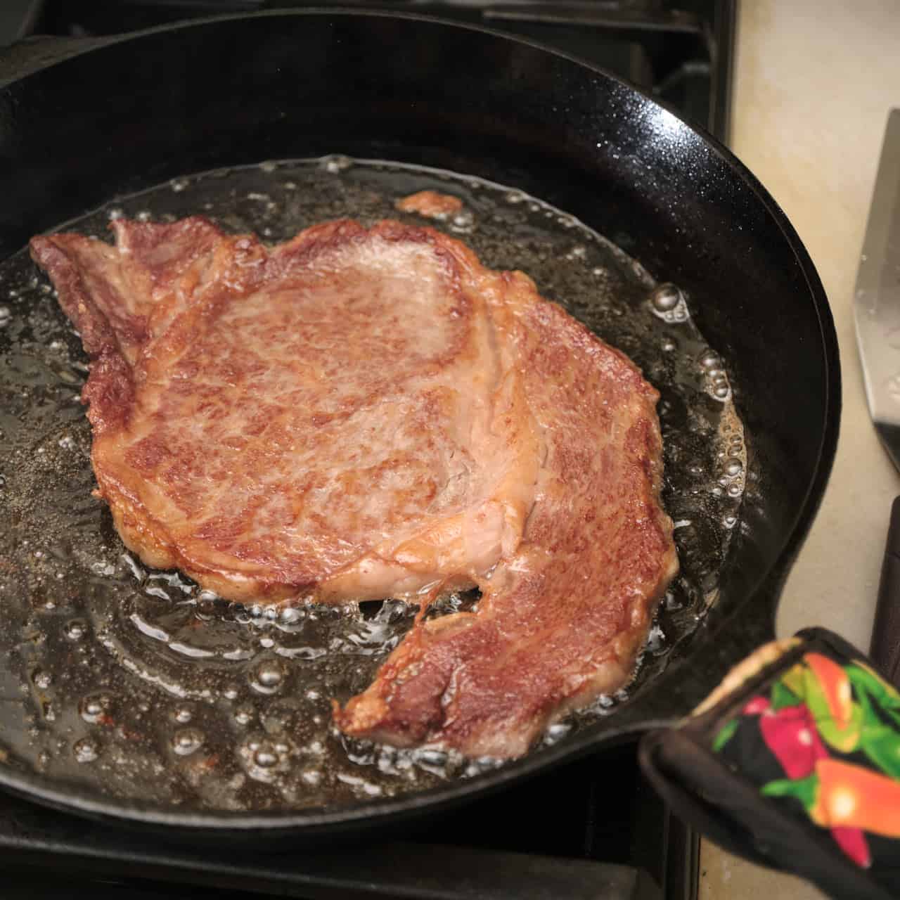 Pan-seared wagyu ribeye steak in a cast iron pan