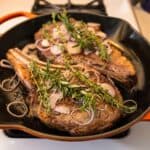Ribeye Steaks in Cast Iron Pan covered with Herbs and Shallots
