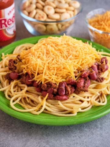 A plate of Cincinnati chili with cheese, oyster crackers, and hot sauce