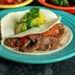 A plate of flank steak tacos with avocado