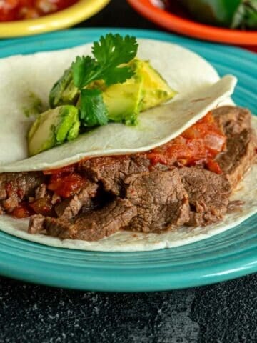 A plate of flank steak tacos with avocado