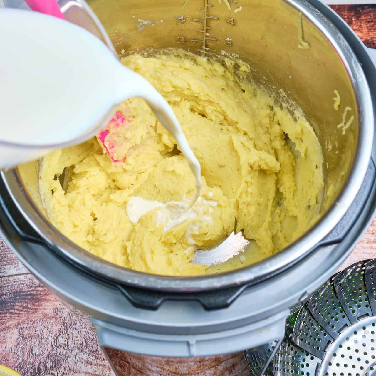 Pouring the milk into the Instant Pot full of riced potatoes