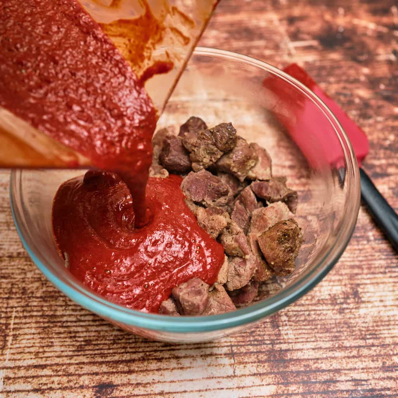 Pouring blended chile sauce over the cooked pork