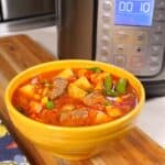 A bowl of Instant Pot Vegetable Beef soup, with an Instant Pot in the background