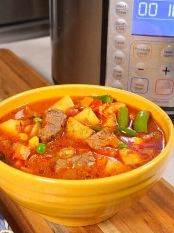 A bowl of Instant Pot Vegetable Beef soup, with an Instant Pot in the background