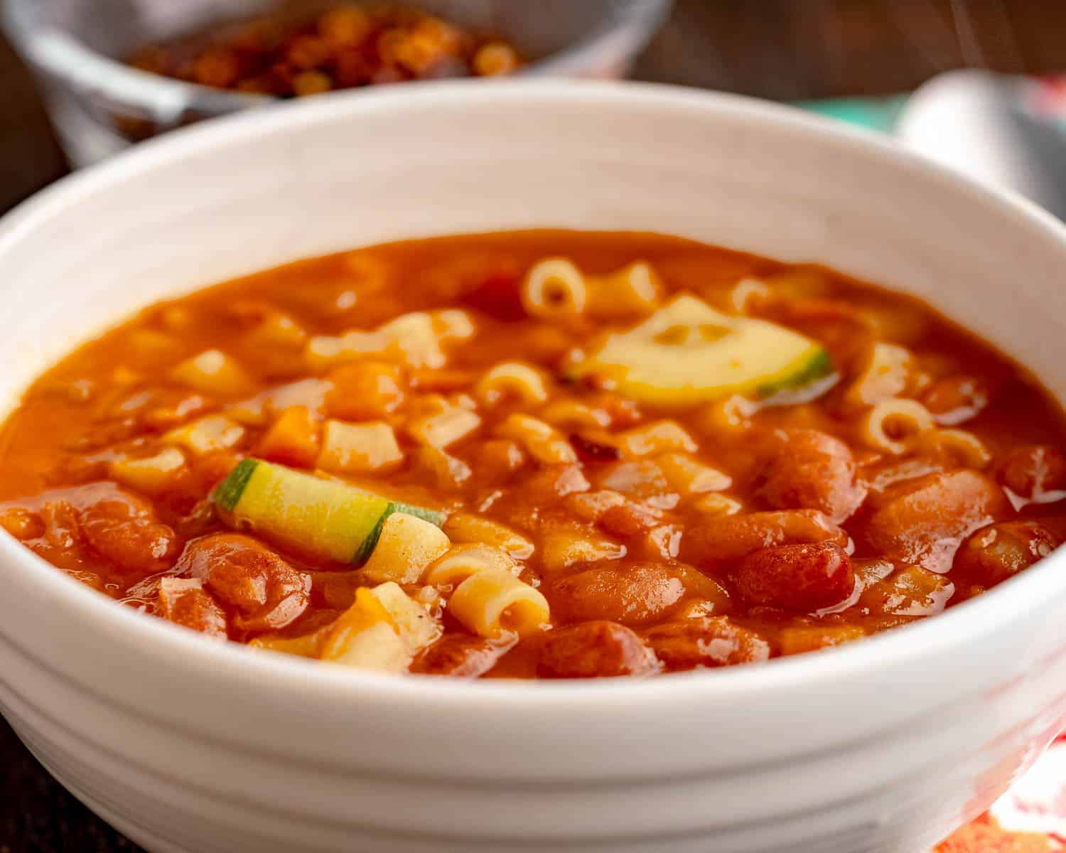 A bowl of minestrone with beans, pasta, and zucchini
