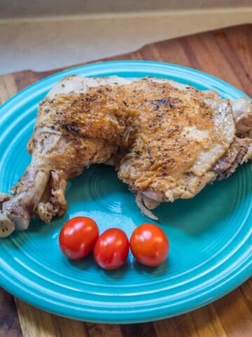 Cooked chicken leg on a plate with cherry tomatoes