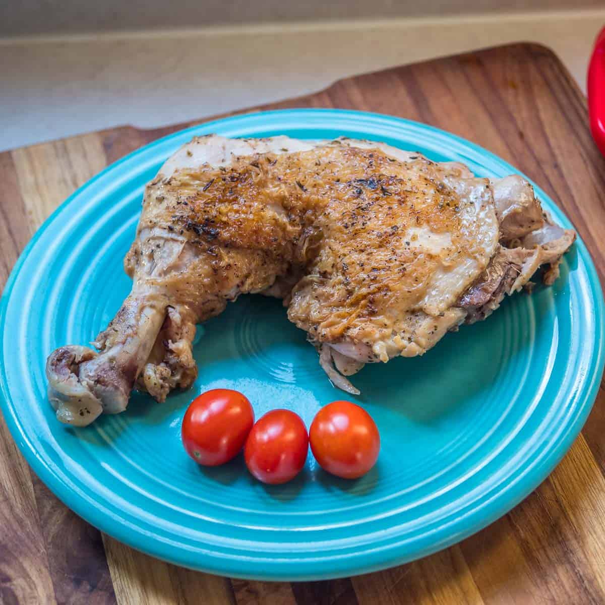 Cooked chicken leg on a plate with cherry tomatoes