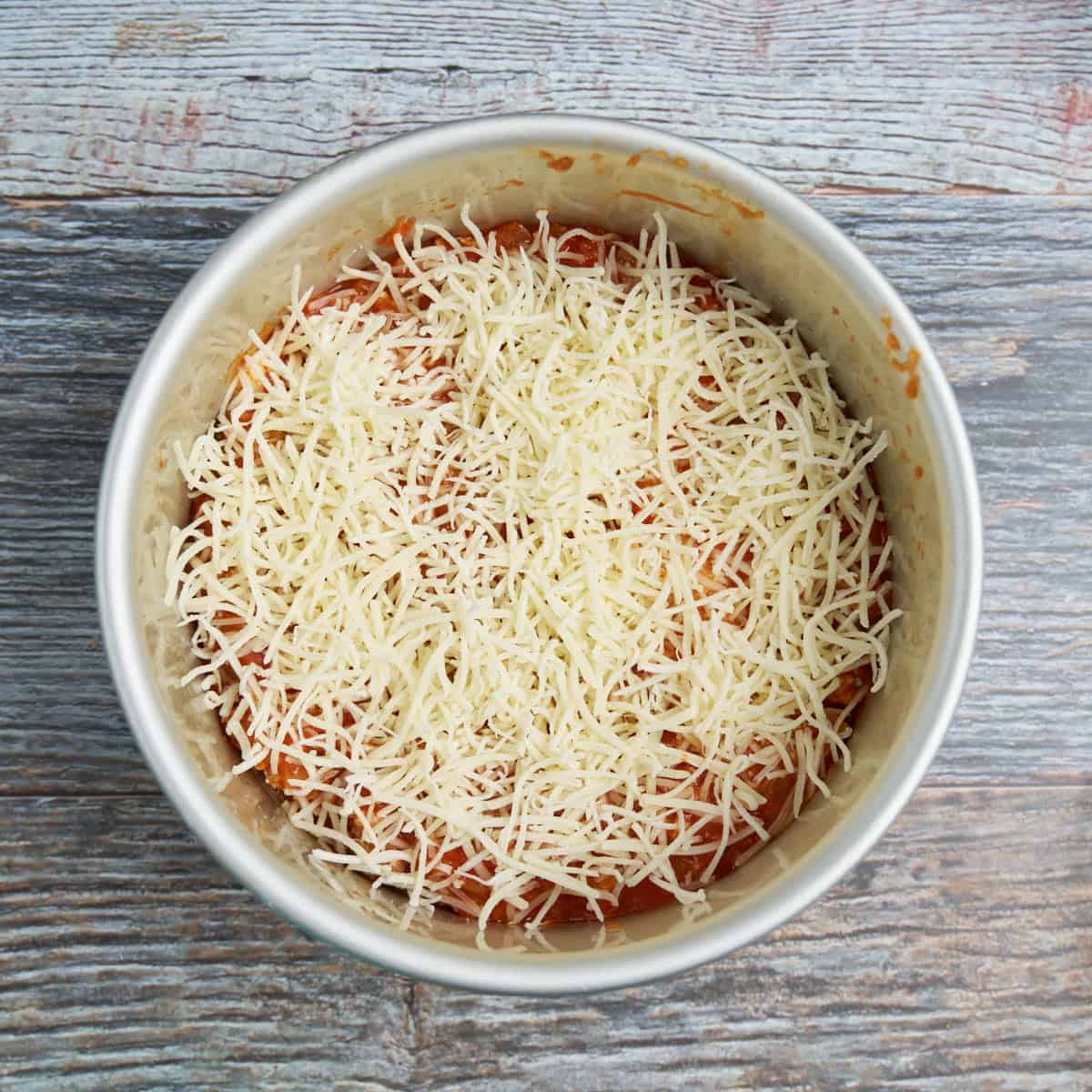 Step 4 - Sprinkle 2 ounces Mozzarella on the sauce