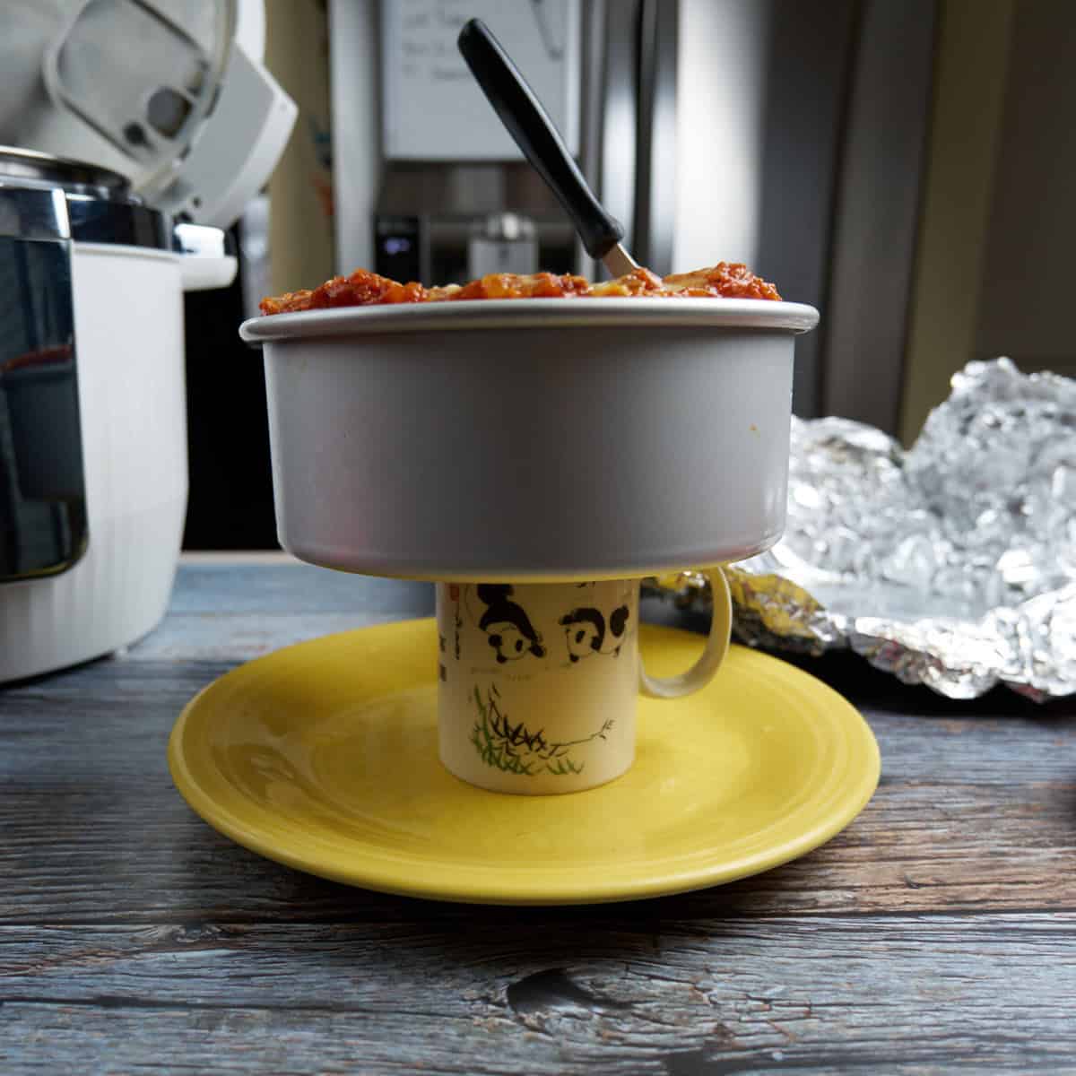 Lasagna pan on a coffee cup, which is lifting the lasagna out from the pan