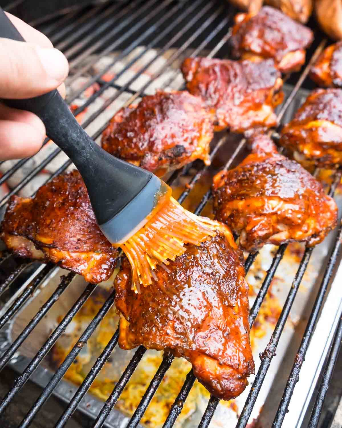 Brushing a row of bbq chicken thighs with more sauce