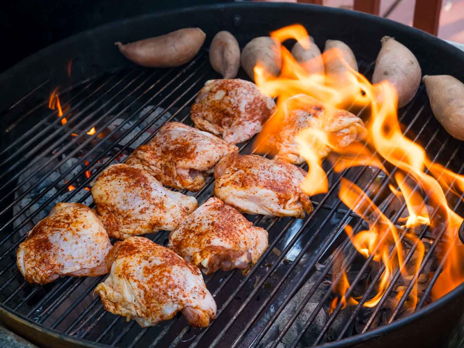 BBQ Chicken thighs on the grill with a wood chip flareup