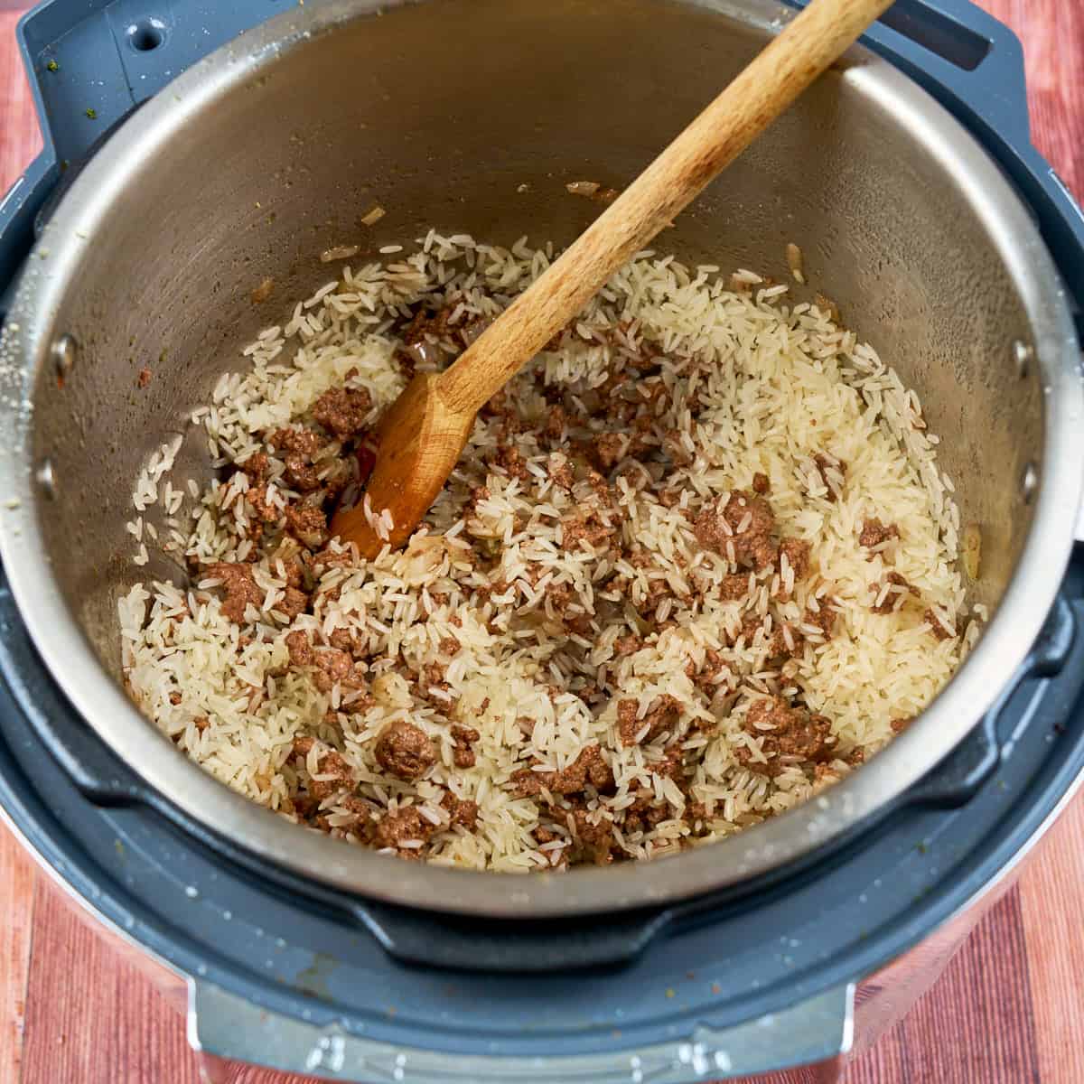 Stirring the rice into the pot with the lamb and spices
