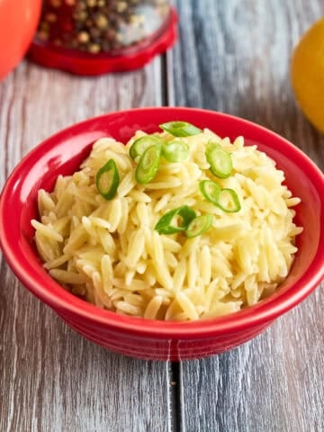 A bowl of Orzo Pilaf with green onions sprinkled on top