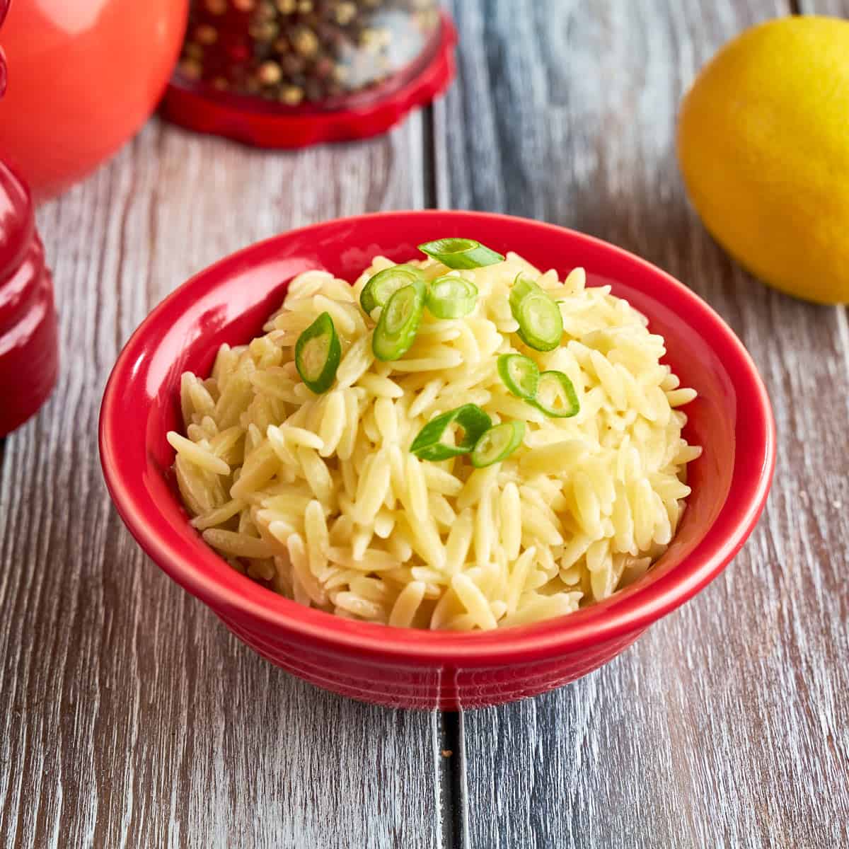 A bowl of Orzo Pilaf with green onions sprinkled on top