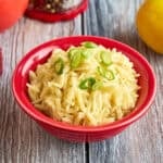 A bowl of Orzo Pilaf with green onions sprinkled on top
