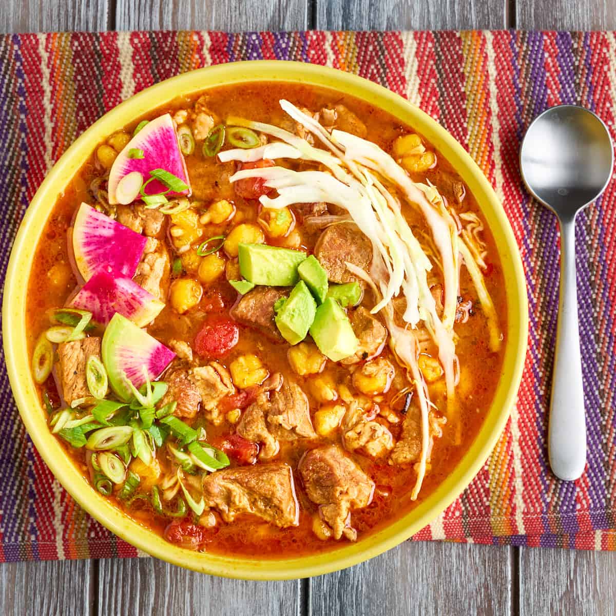 A bowl of Instant Pot Pozole with shredded cabbage, radishes, and avocado