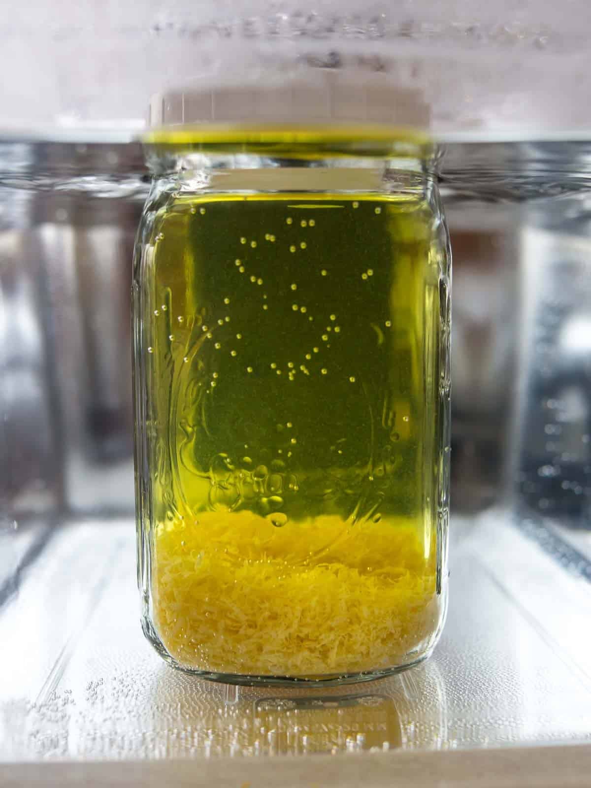 Jar of everclear and lemon zest in water bath up to bottom of lid