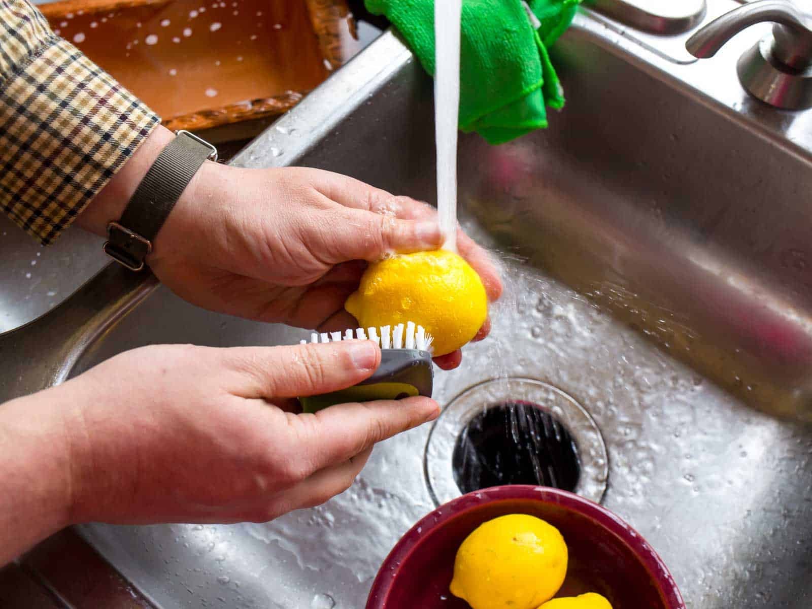 Scrubbing lemons under running water