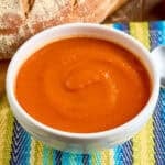 A bowl of Instant Pot Tomato Soup with a spoon and a loaf of bread