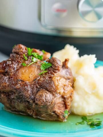 A cooked piece of oxtail with mashed potatoes