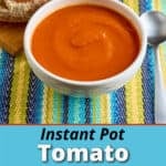 A bowl of Instant Pot Tomato Soup with a spoon and a loaf of bread