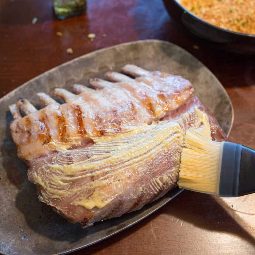 Brushing rack of lamb with mustard