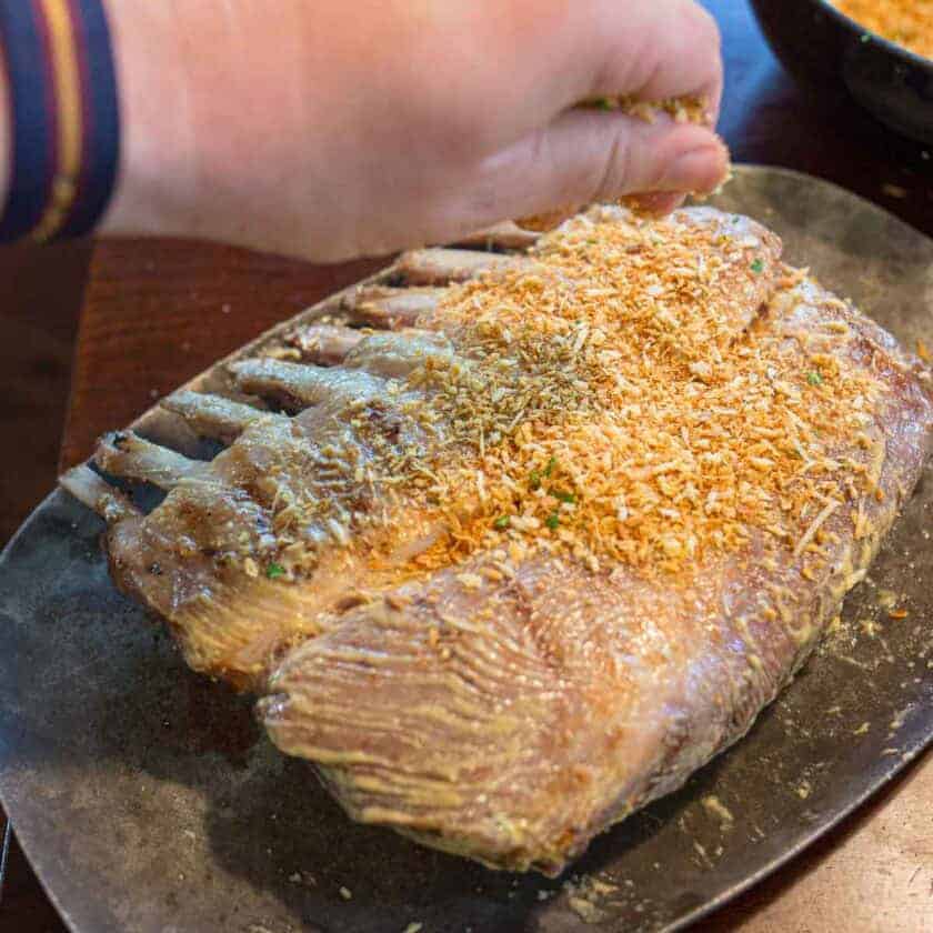 Sprinkling toasted panko crumbs on the rack of lamb