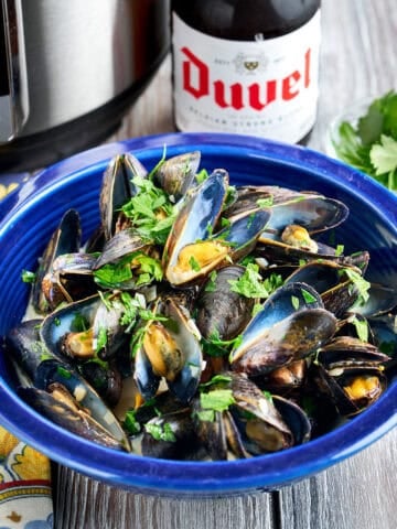 A bowl of Instant Pot Belgian Mussels with a beer