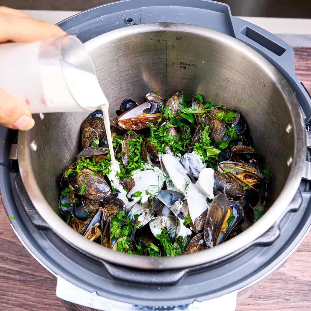Pouring cream over the cooked mussels in an Instant Pot