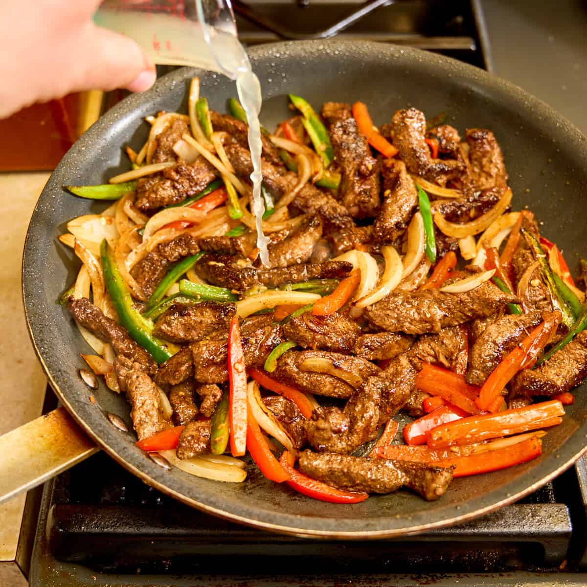 Pouring lime juice into a pan of fajitas