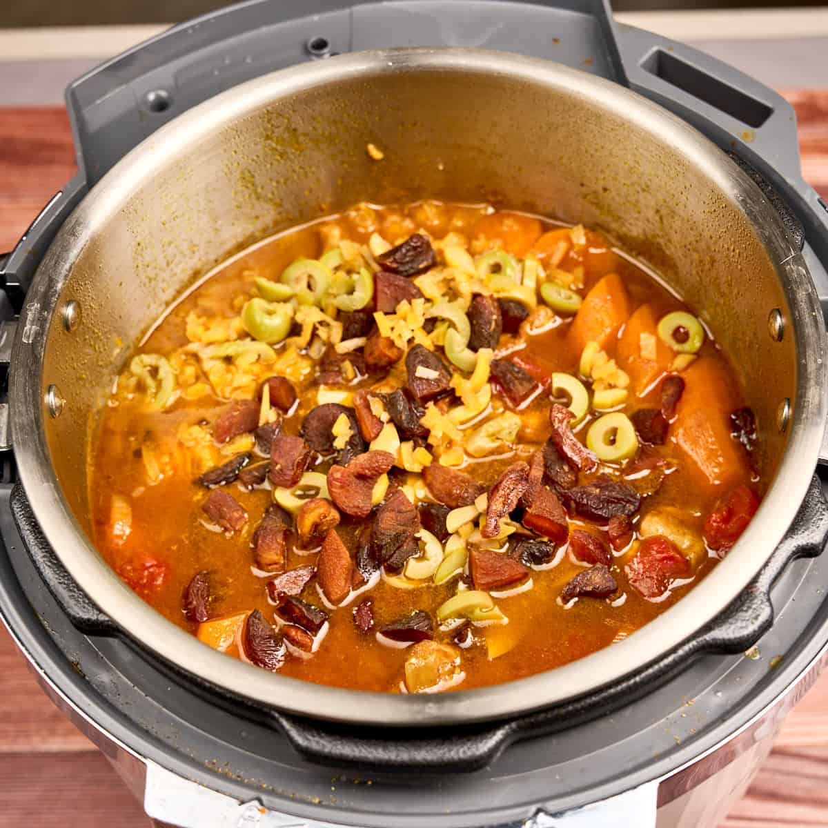 Adding the apricots, olives, and preserved lemon to the pot