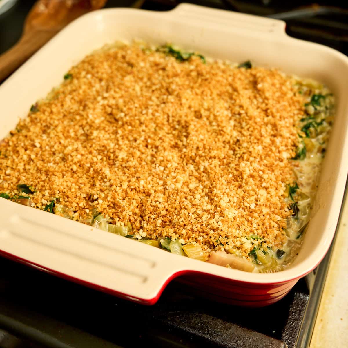 Chard and milk sauce in a baking dish topped with toasted panko and ready for the oven
